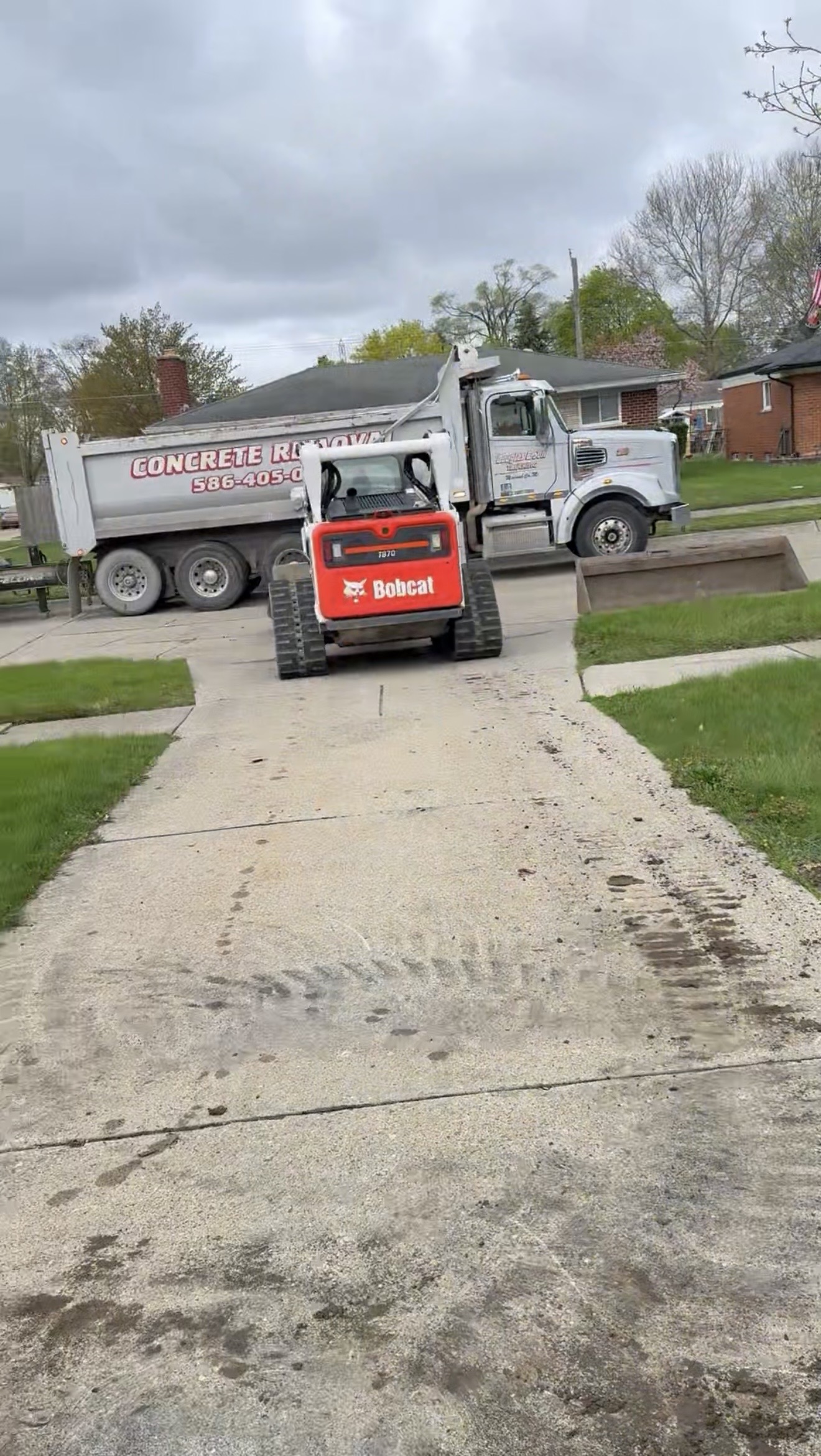Bobcat and dump truck on site for concrete removal and replacement